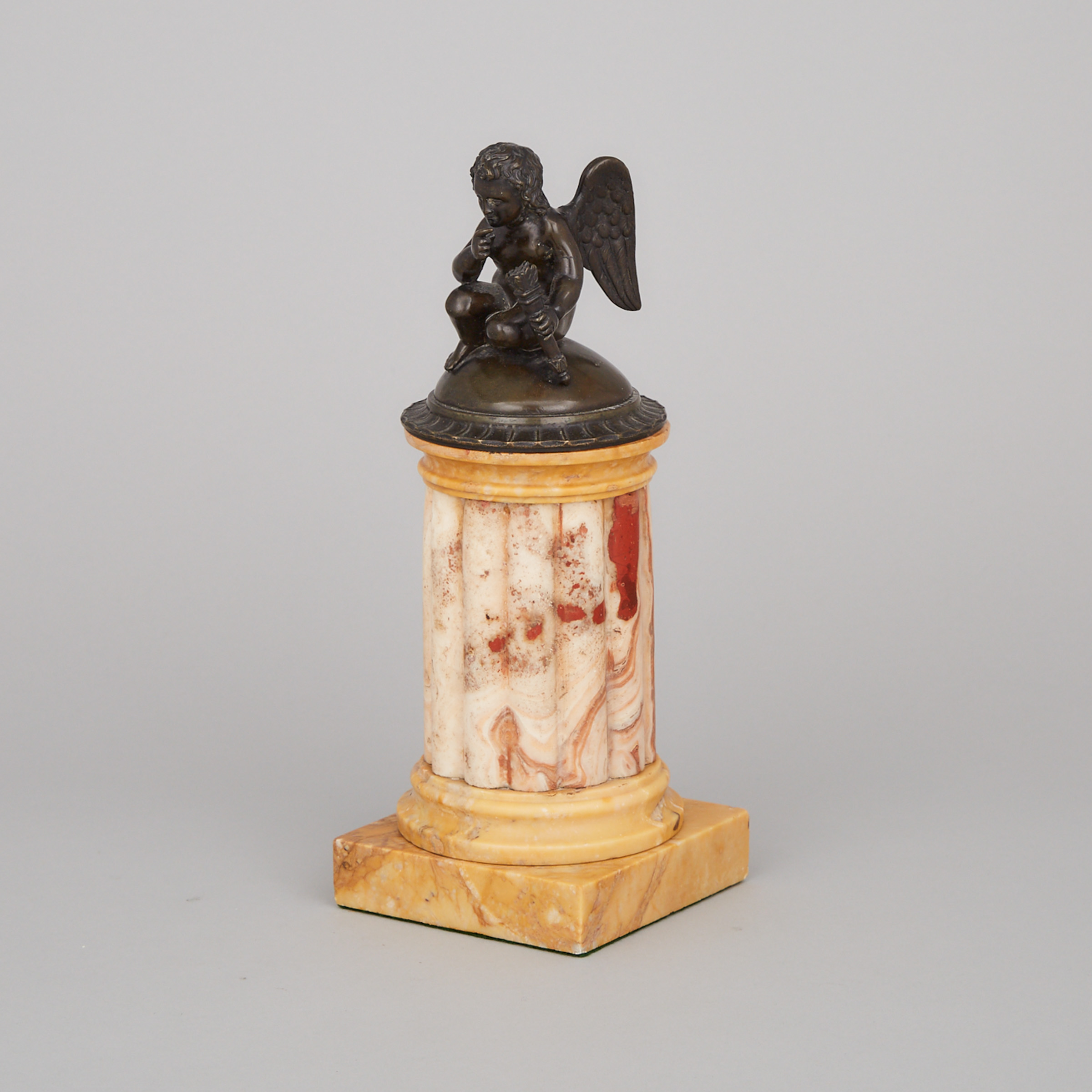 After the Ancient Patinated Bronze Model of Cupid Seated Atop a Sienna Marble Column Form Base, 19th century