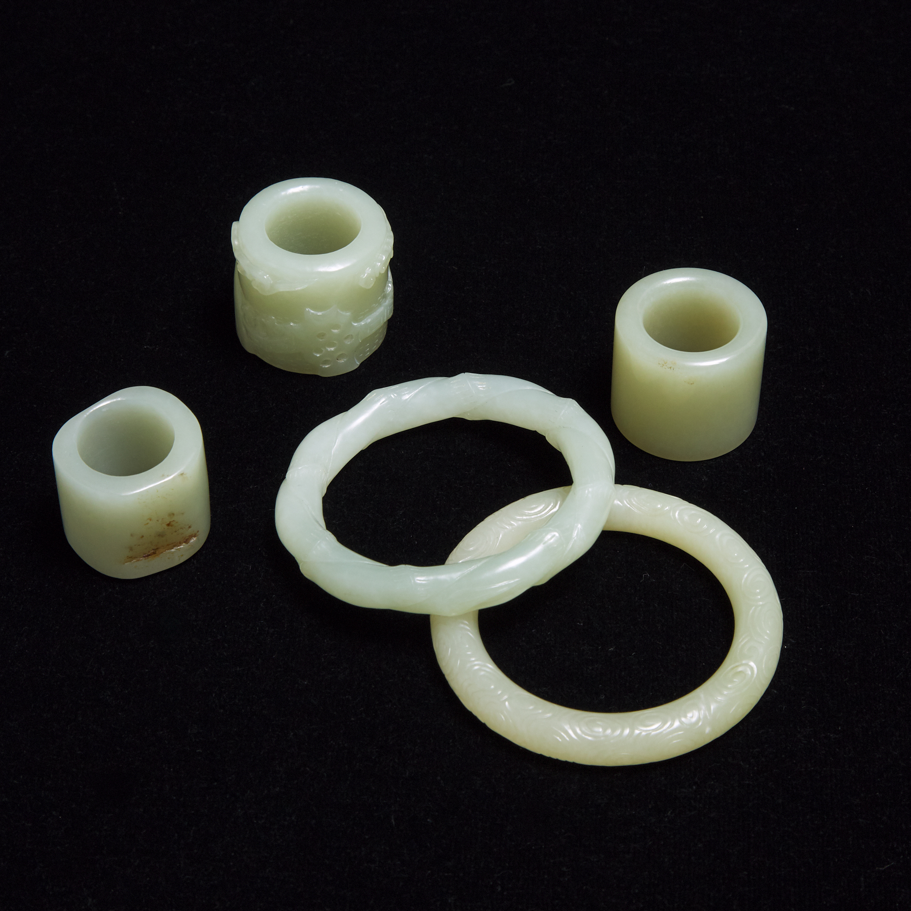 A Group of Three Pale Celadon Jade Archer Rings, together with Two Pale Celadon Jade Bangles