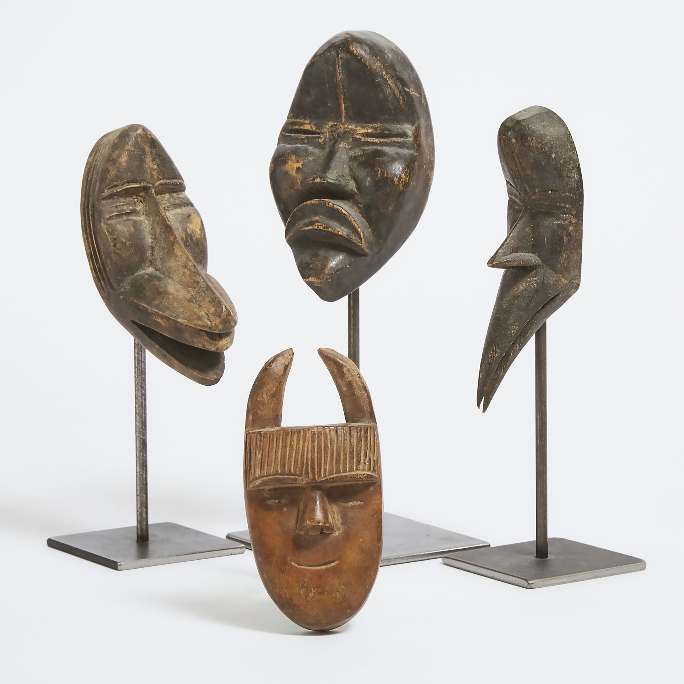 Three Dan Passport Masks, Ivory Coast/Liberia, West Africa, early to mid 20th century together with a Toma Passport Mask, Guinea/Liberia, West Africa, mid to late 20th century