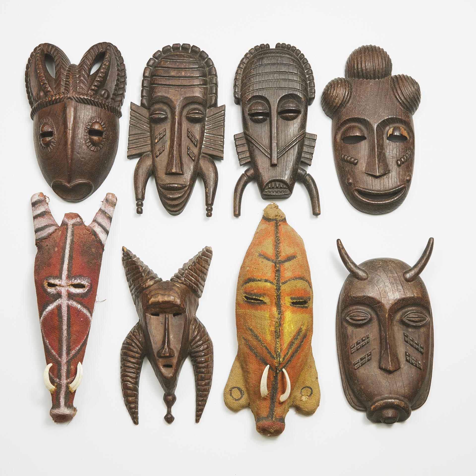 A Group Six Decorative African Masks, together with two Papua New Guinea-style papier maché and burlap boar masks, all late 20th century
