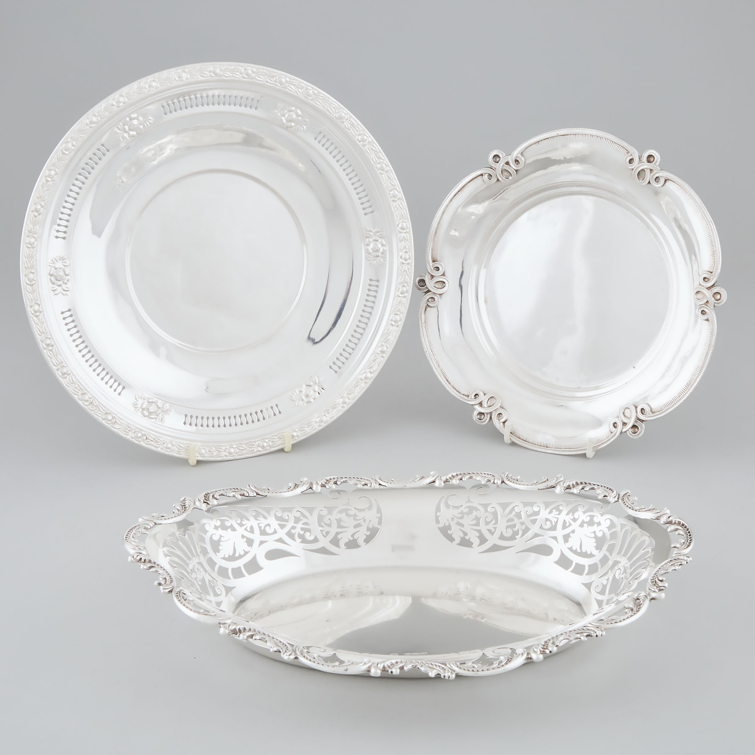 Edwardian Silver Pierced Oval Bread Dish, William Hutton & Sons, London, 1901, together with a German Silver Shaped Circular Dish and a North American Cake Plate, late 19th/early 20th century