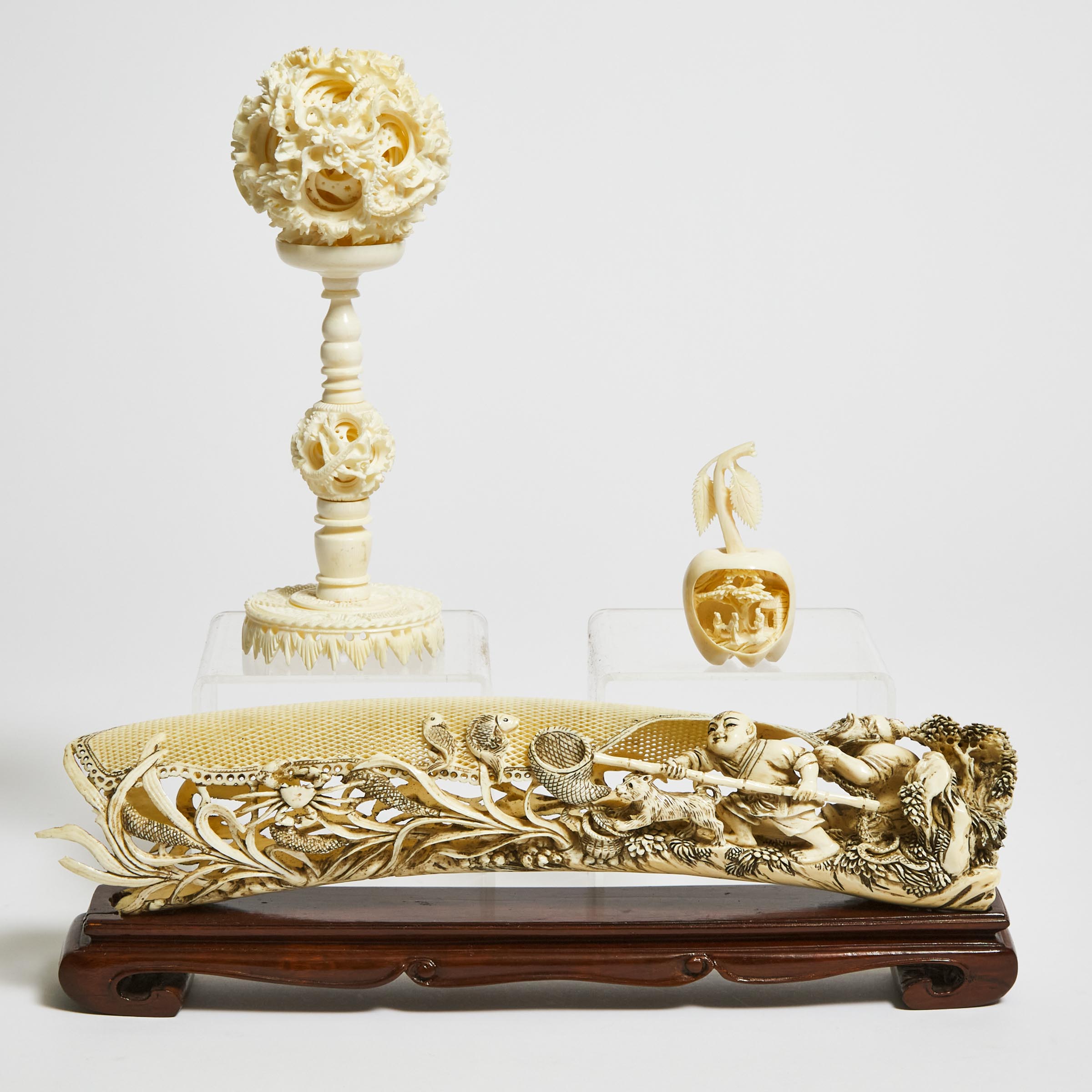 An Ivory Puzzle Ball, Together With a Carving of Two Fisherman and a Carved 'Landscape' Fruit, Early 20th Century