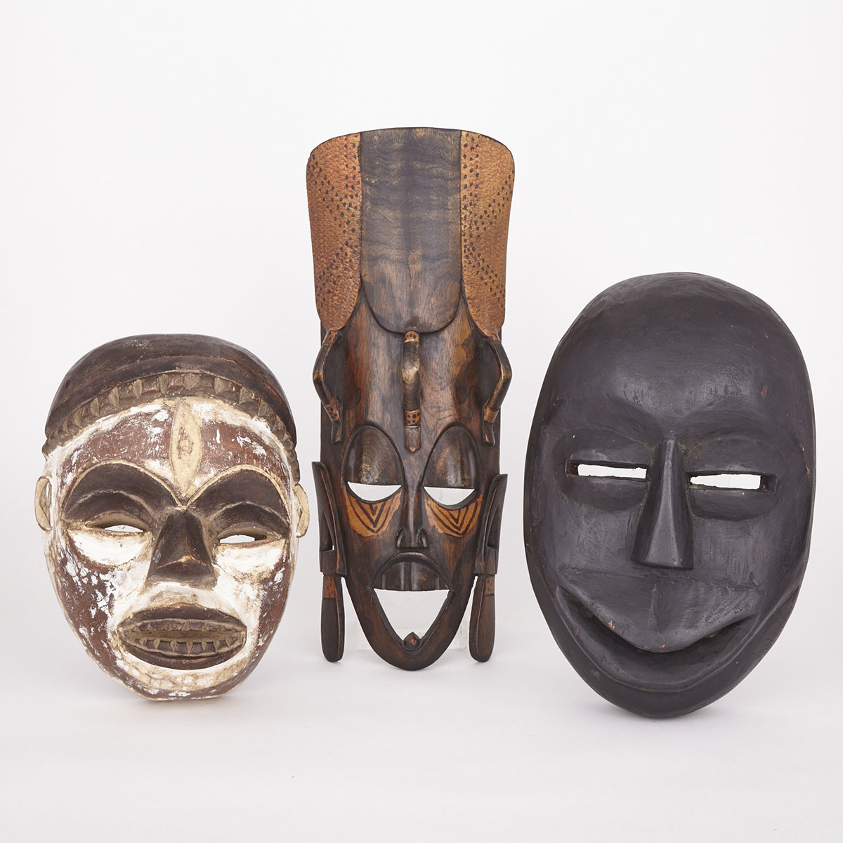 Two Carved and Painted Wood Masks together with a Carved and Stained Wood Mask, Africa, 20th/21st century