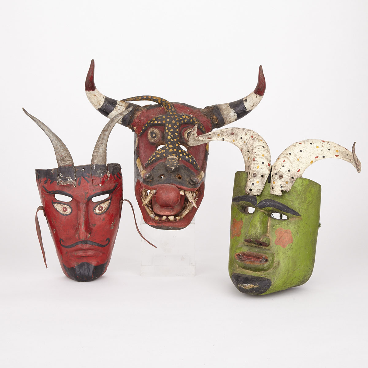 Three Carved and Painted Wood Masks; Devil mask with goat horns, Figurative Mask with ram horns and a zoomorphic mask with bull horns and inset teeth and carved wood canines, Mexico, 20th century